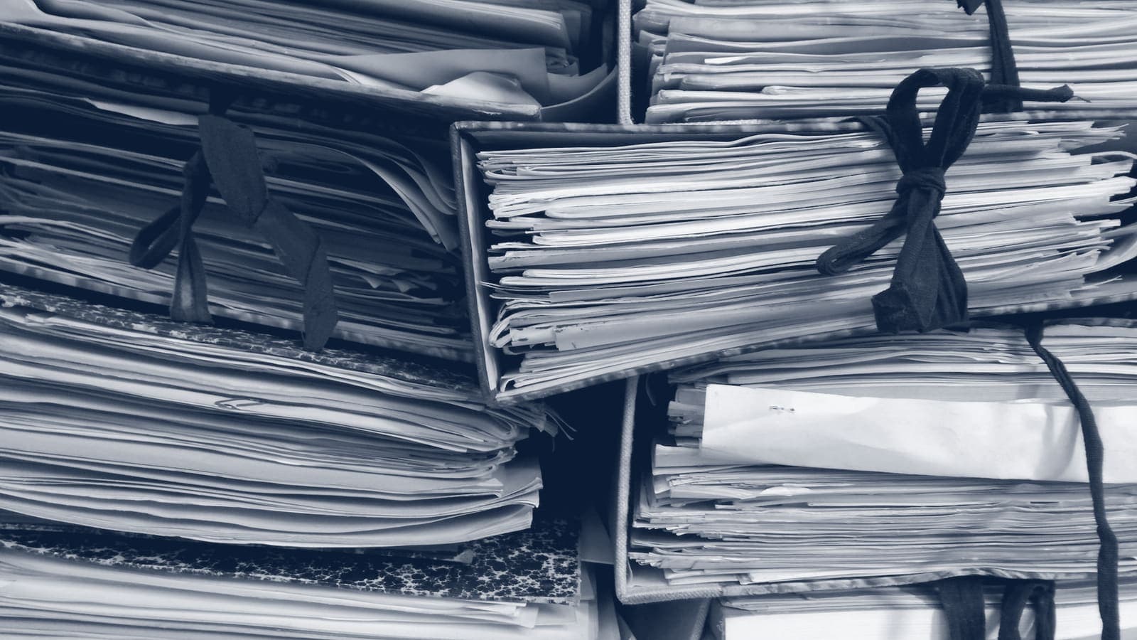 Stacks of paper files in folders tied shut with ribbon